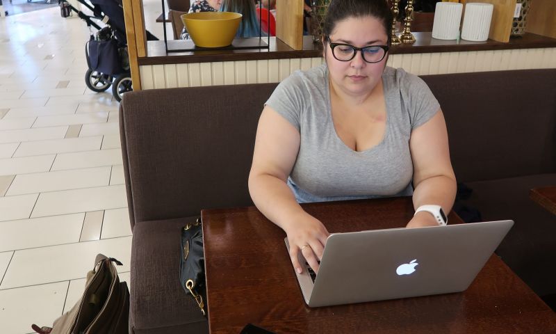 Ung dame sitter og skriver på en laptop på en kafé