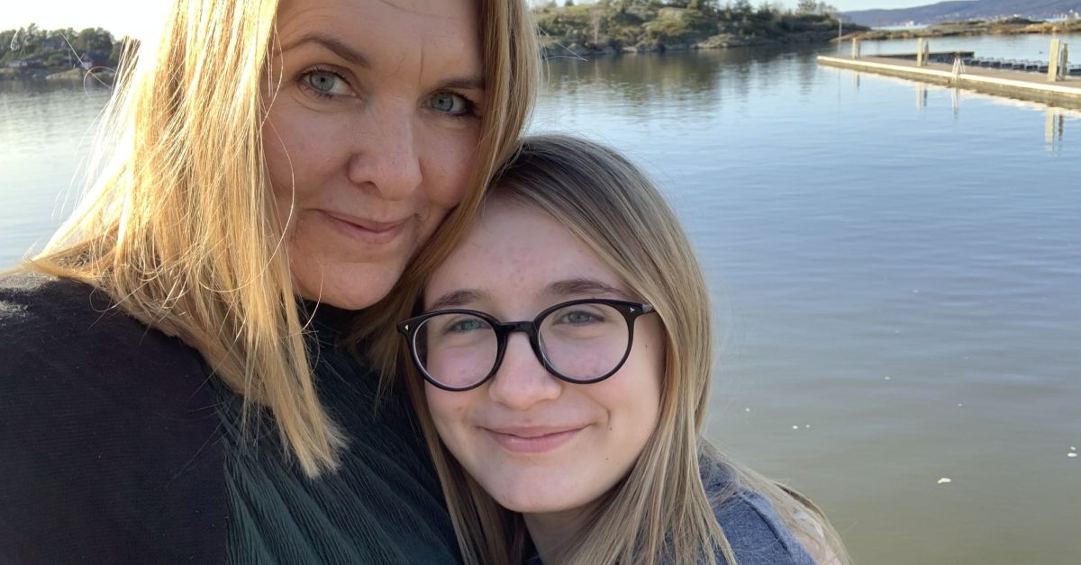 Smilende mor og datter med et vann i bakgrunnen