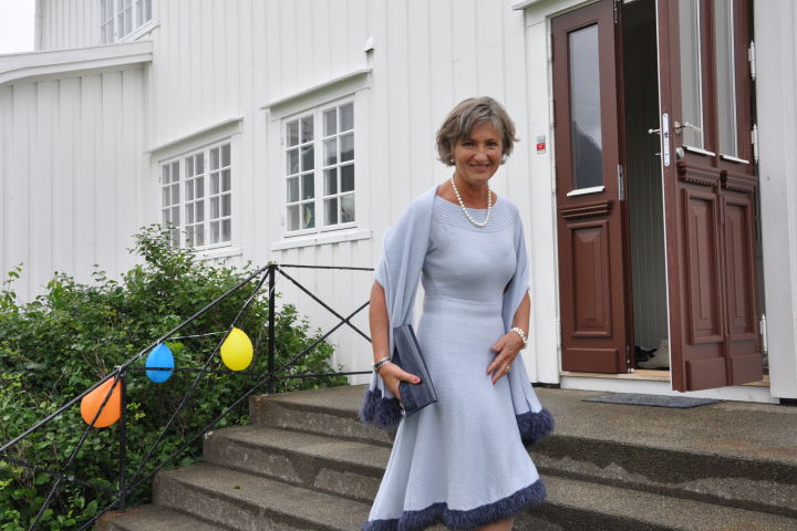 Festkledd smilende dame i lyseblå strikkekjole