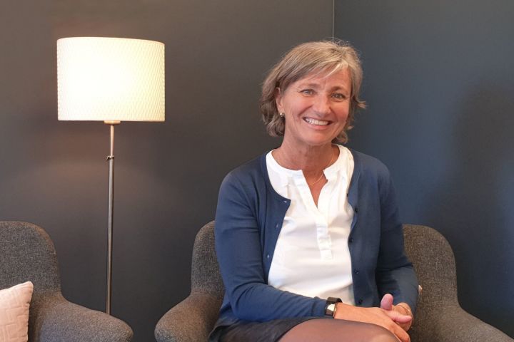 Smilende dame sittende i stol ved siden av en lampe