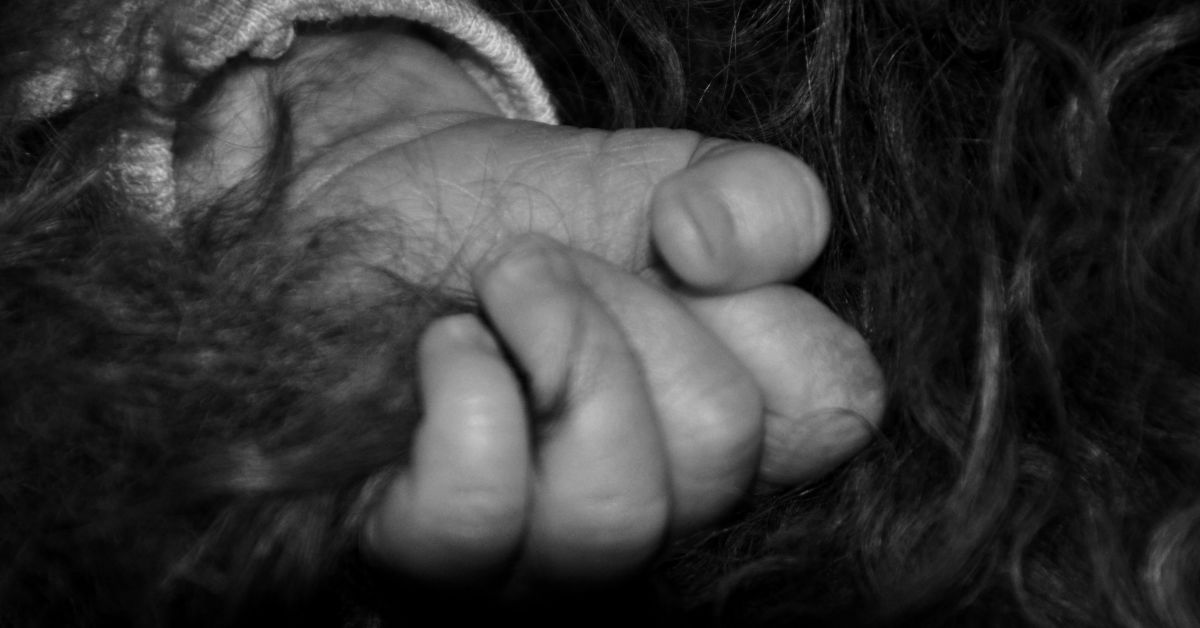 Babyhånd som griper rundt mørkt krøllete hår