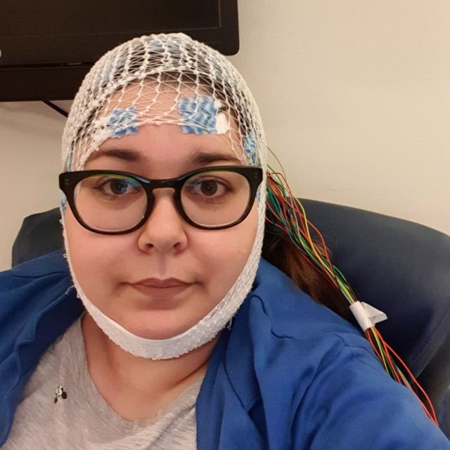 Portrett av ung dame med nettingstrømpe og elektroder på hodet fordi hun gjennomfører telemetriundersøkelse